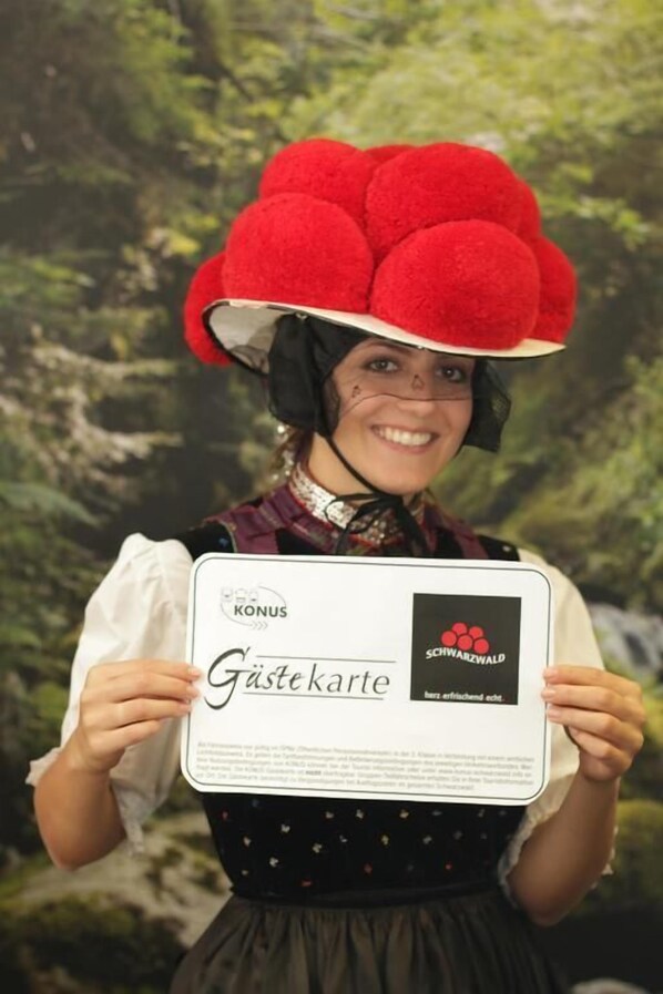 A person holding a certificate with the text "Gästekarte" and "KONUS" visible. - Hotel Adler - Post (Baiersbronn)