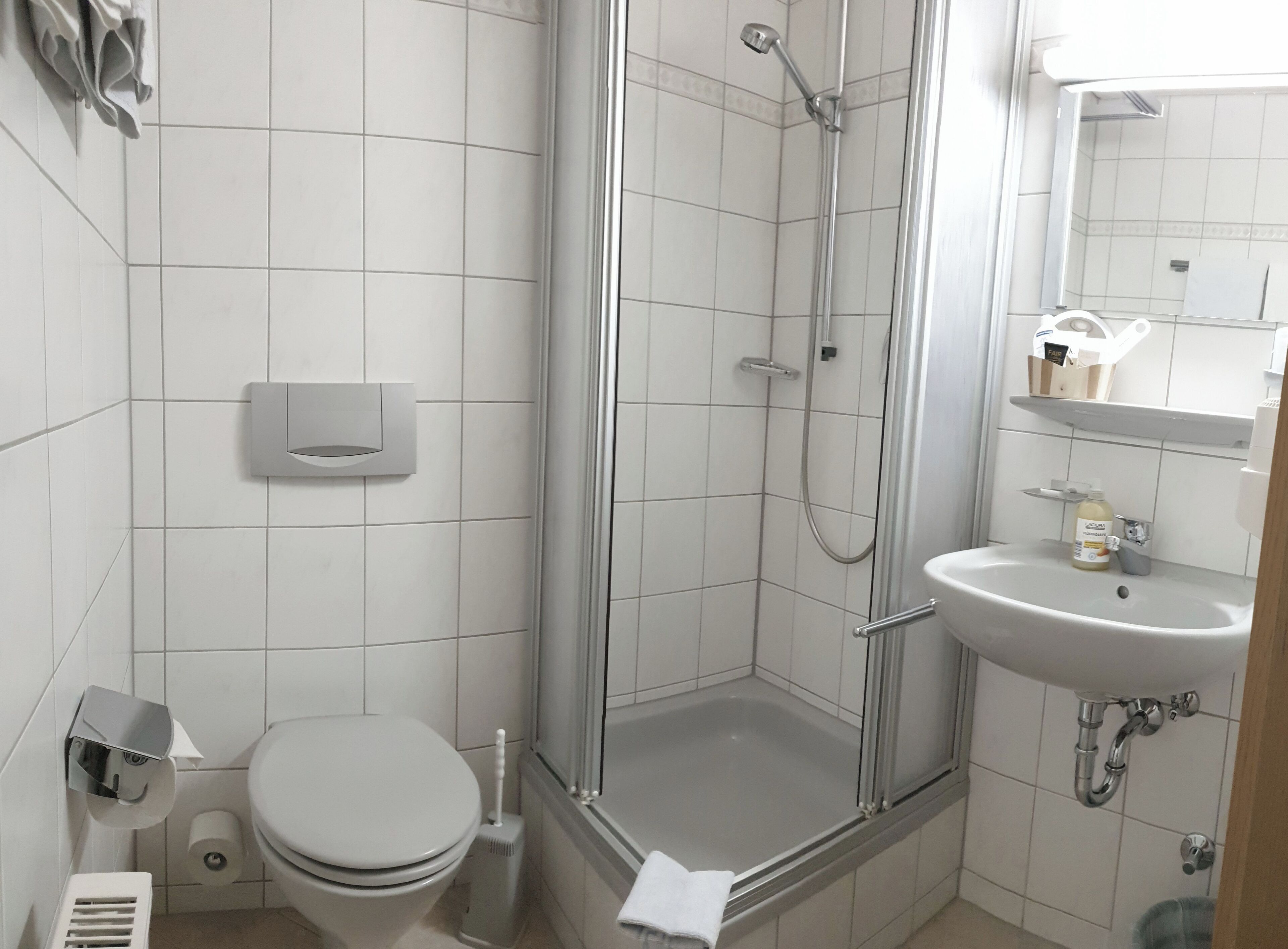 A modern bathroom with a toilet, a shower, and a sink.
