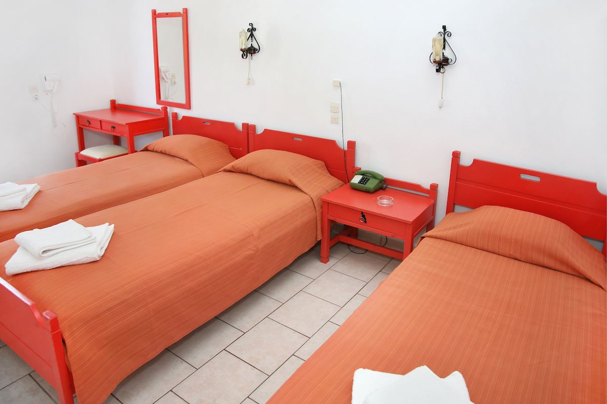 A room with two beds, a red vanity, a mirror, and a telephone.