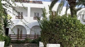 En hotelindgang med en stensti, der fører til en hvid bygning med balkoner og et skilt, der viser "ASTERIAS HOTEL".