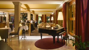 A grand lobby with a piano, dining area, and a bar.