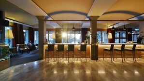A modern hotel lobby with a bar area, seating, and large windows.