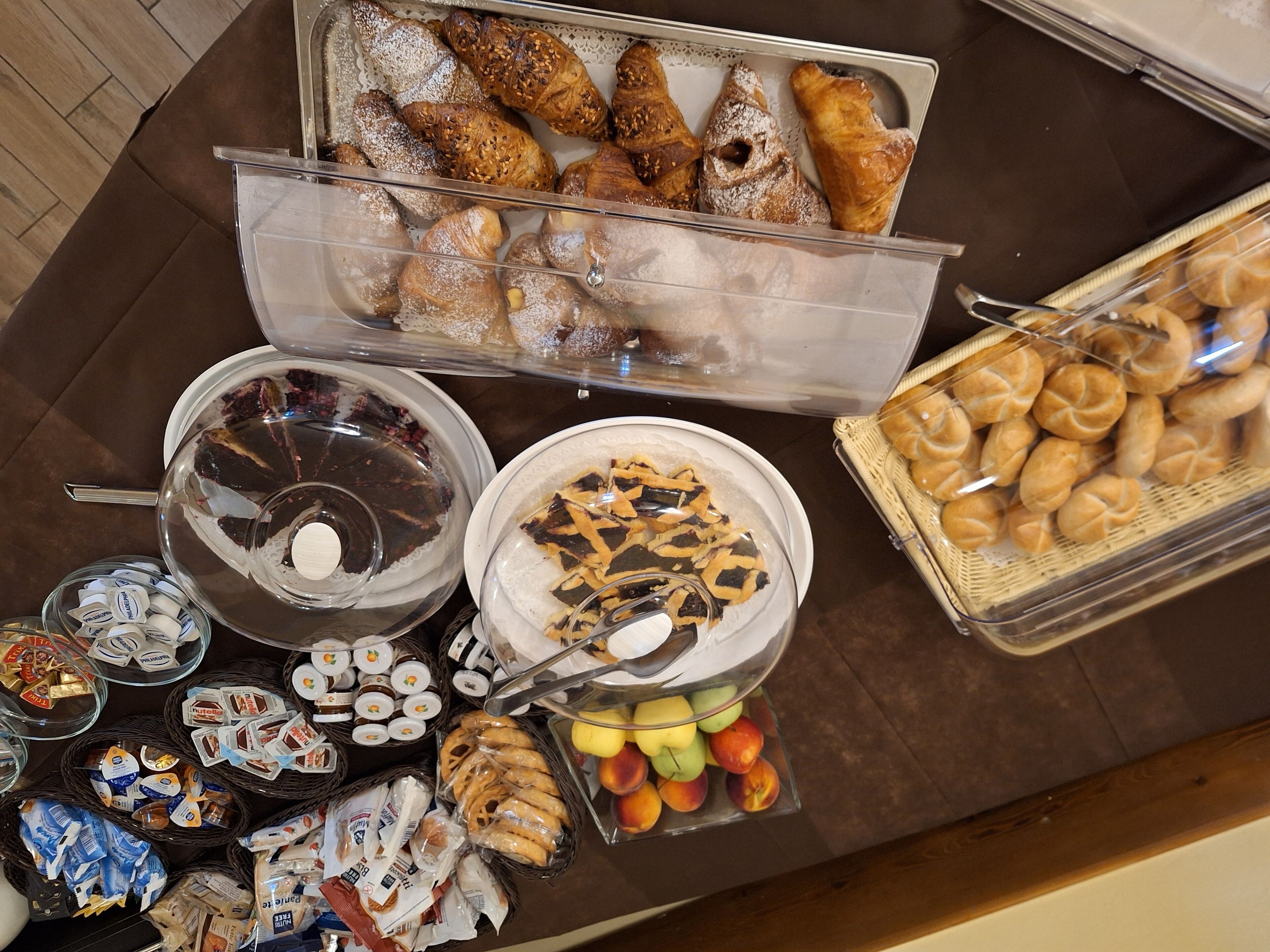 A buffet with various food items including pastries, fruits, and condiments.
