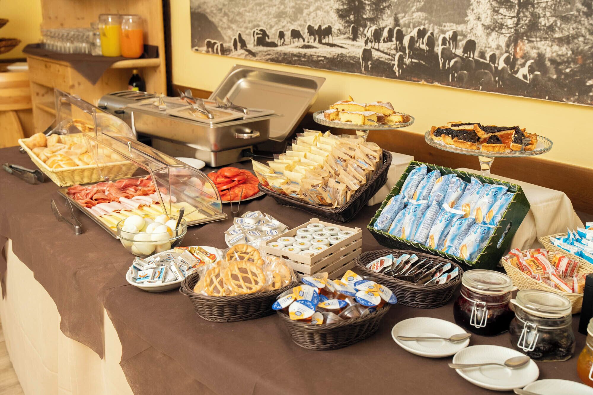 A buffet with various food items including meats, cheeses, and pastries.
