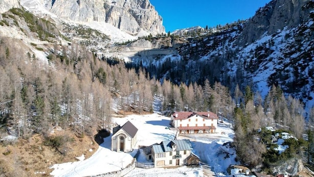 Un village de montagne où le sol est recouvert de neige, avec une église et des maisons aux toits rouges.