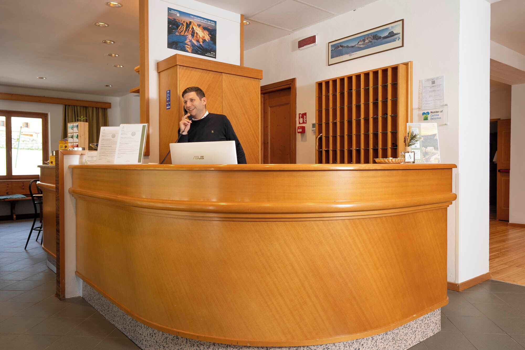 A reception desk with a wooden finish, a laptop, and a framed picture on the wall.