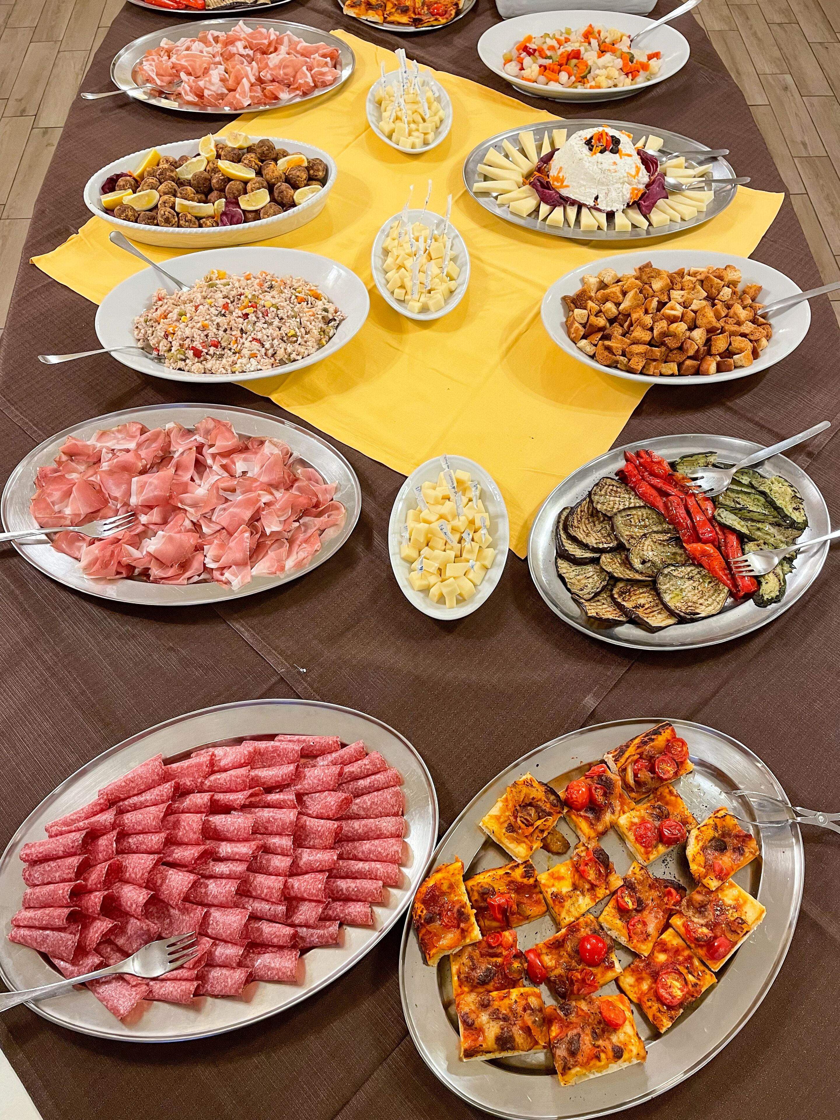 A buffet table with various dishes including meats, cheeses, and vegetables.