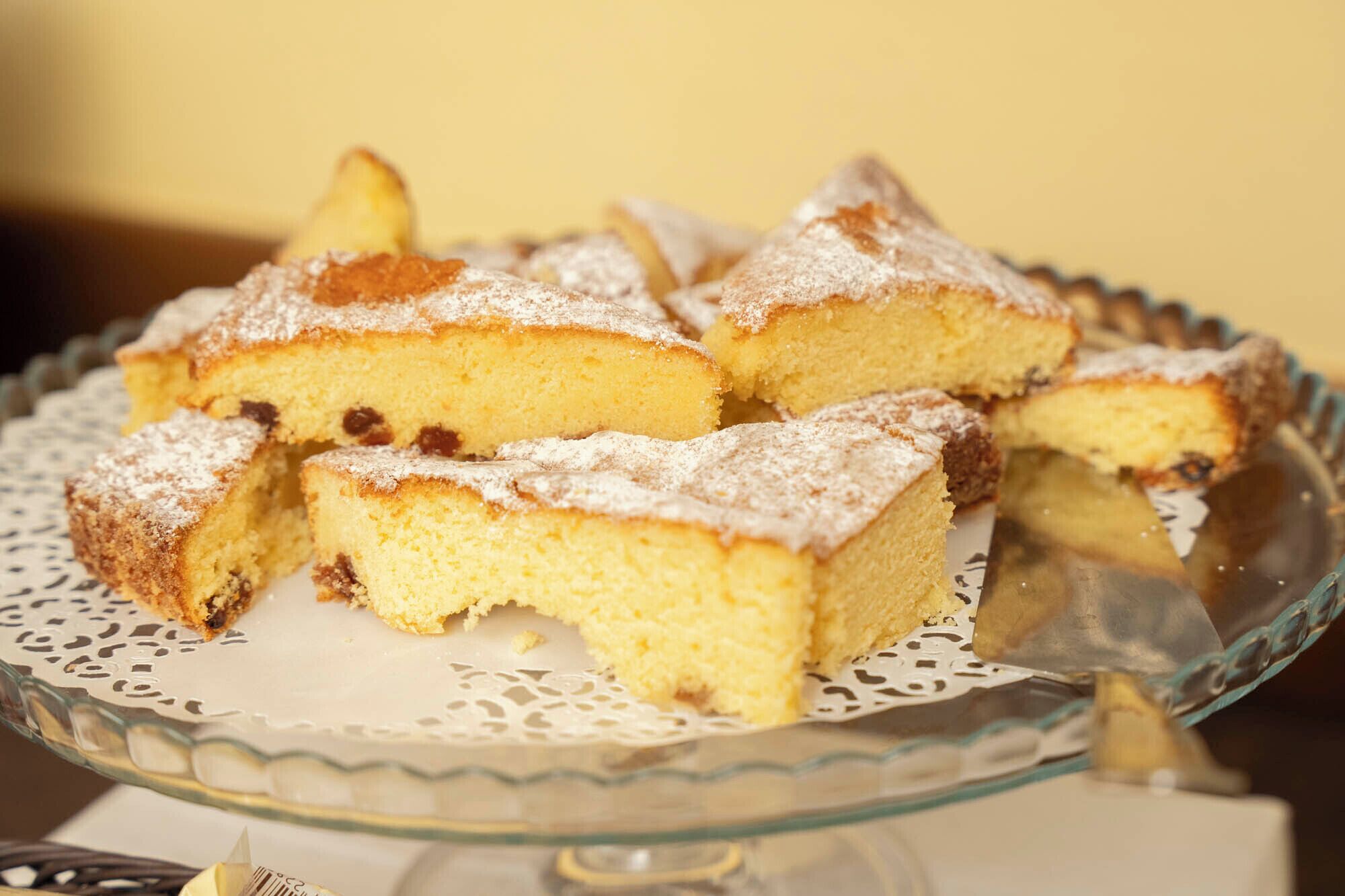 Un soporte de vidrio para pasteles con varios trozos de pastel sobre un encaje.