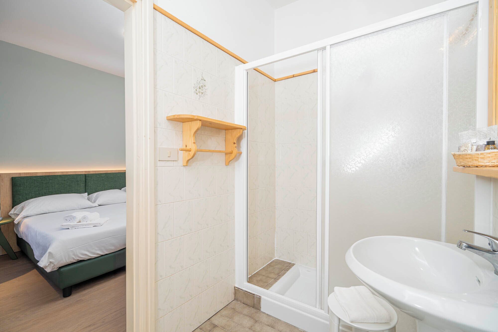 A hotel room with a bed, a shower, and a sink.