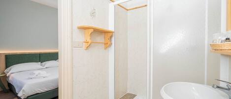 A hotel room with a bed, a shower, and a sink.