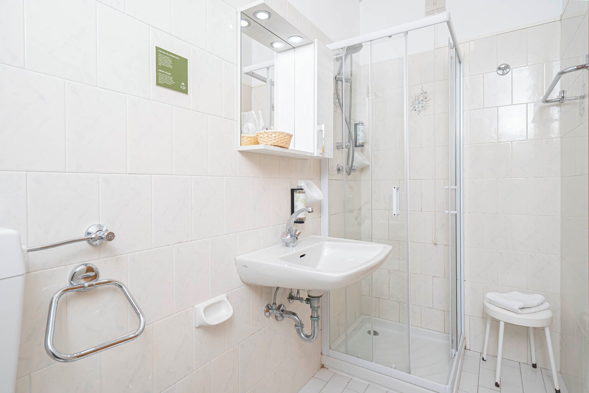 A modern bathroom with a glass-enclosed shower, a white sink, and a towel rack.