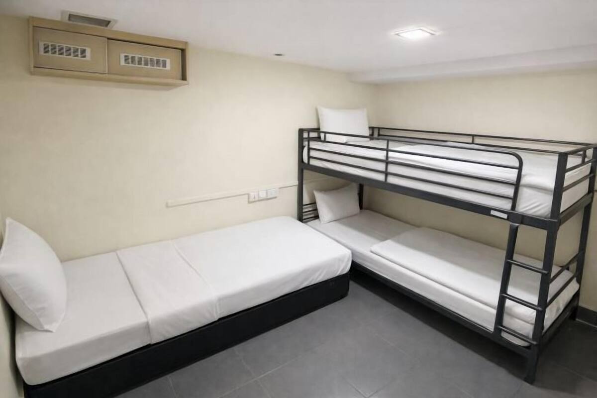 A bunk bed room with a single bed on the left and a bunk bed on the right. There is a small cabinet above the single bed.