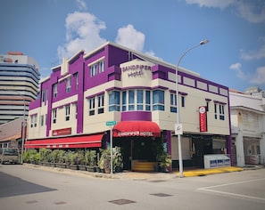 A hotel with a purple and white facade, a red awning, and a visible entrance. - Sandpiper Hotel (Singapore)