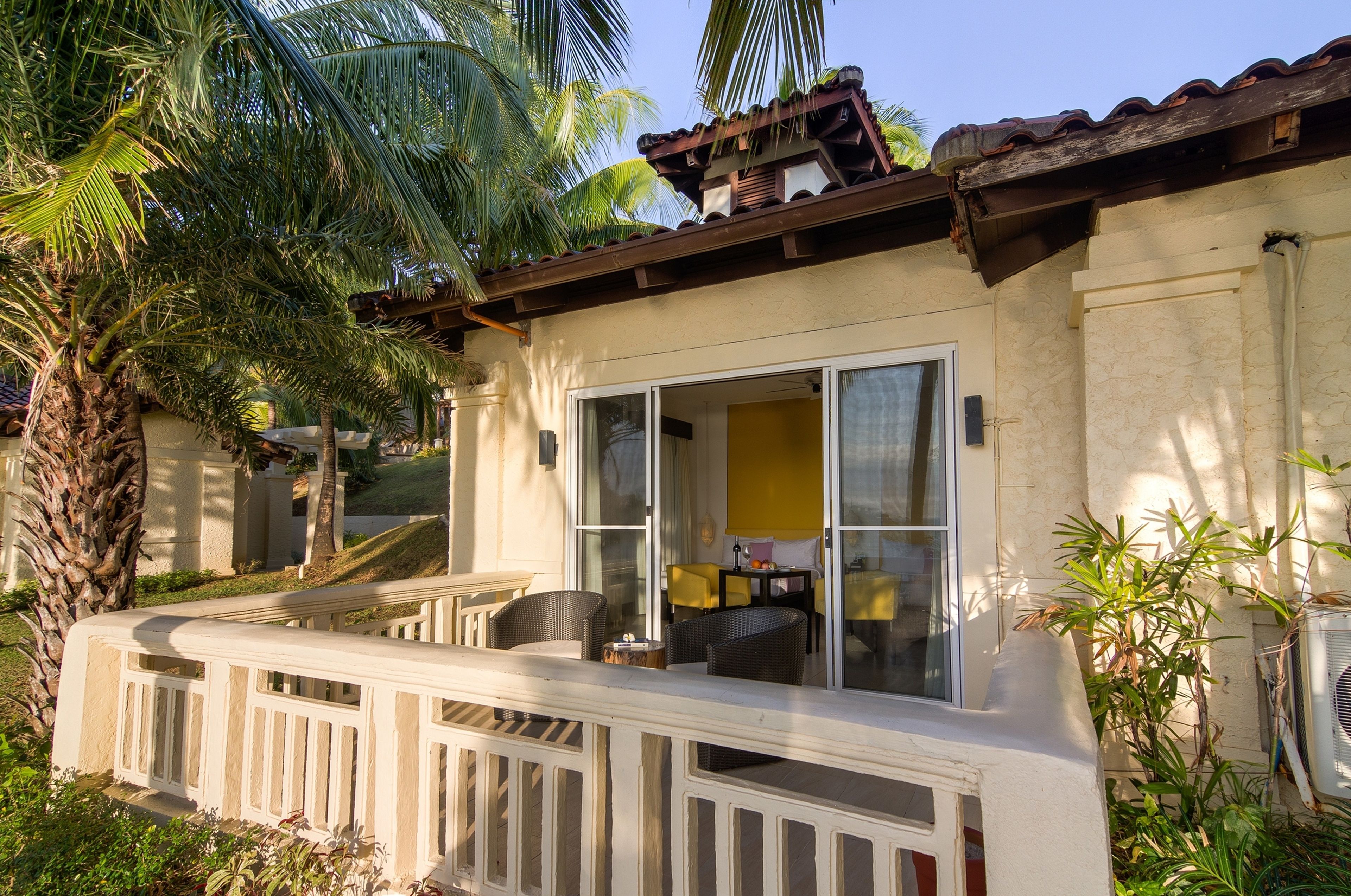 Una casa con balcón, puerta corrediza de vidrio y un pequeño espacio exterior con mobiliario.