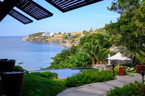 A coastal view with a swimming pool, lush greenery, and a clear sky. - Club Punta Fuego (Nasugbu)