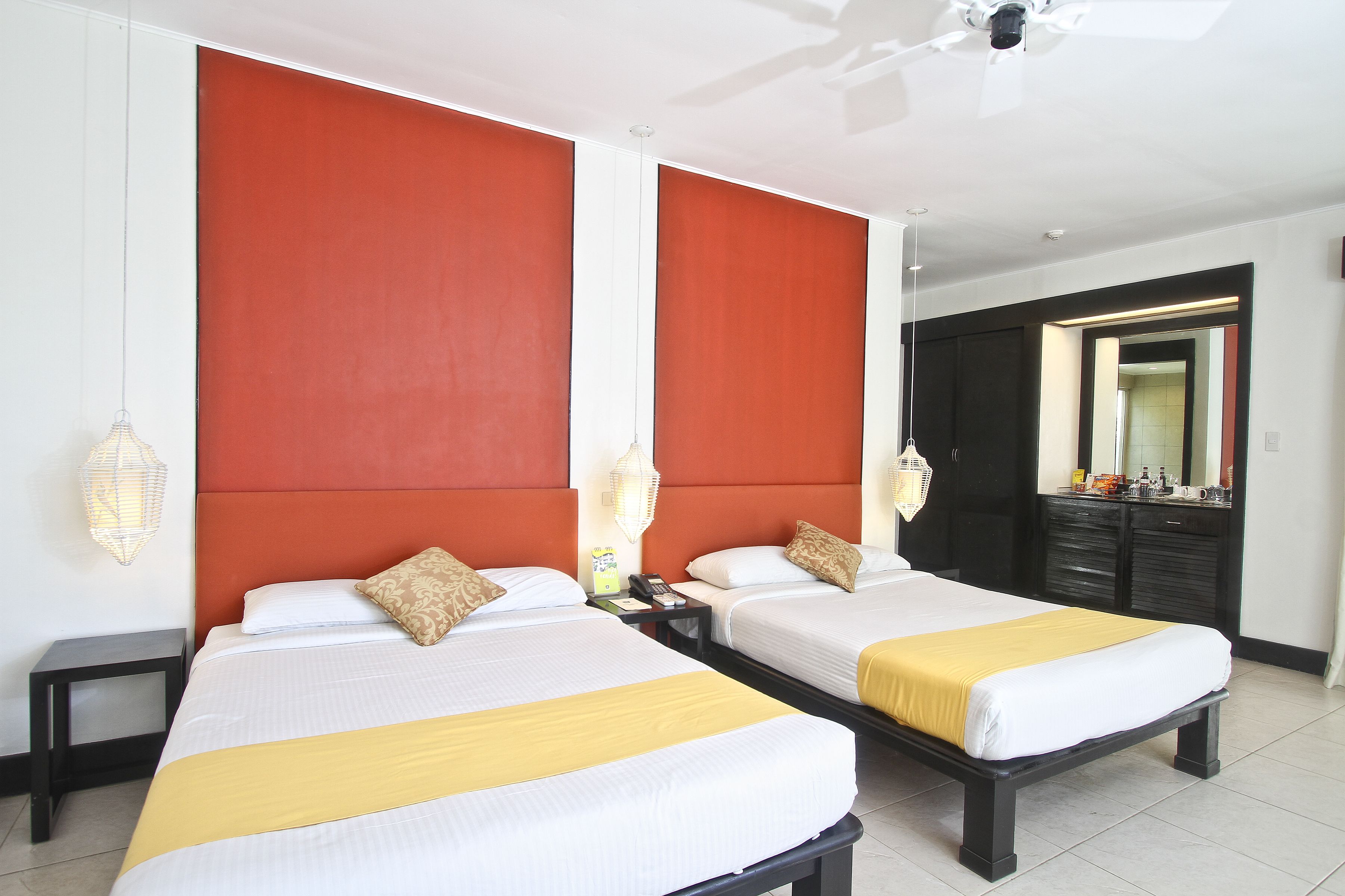 A hotel room with two beds, a wardrobe, a mirror, and a nightstand.