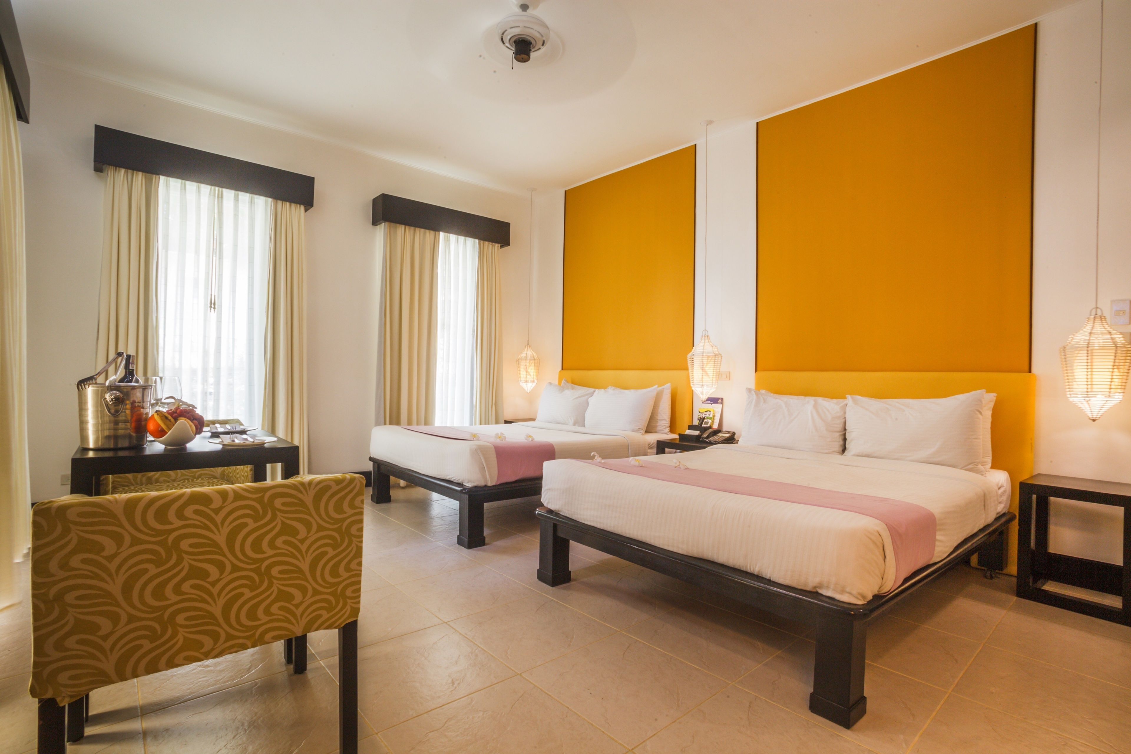A hotel room with two beds, a dining table, and a chair.