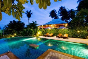 Une piscine avec des chaises longues et un bâtiment en arrière-plan.