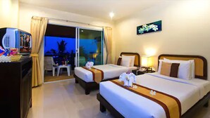 Habitación de hotel con dos camas, un escritorio con computadora, una silla y vista al exterior.