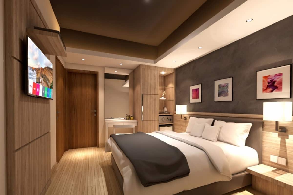 A modern hotel room with a large bed, a desk, and a TV mounted on the wall.