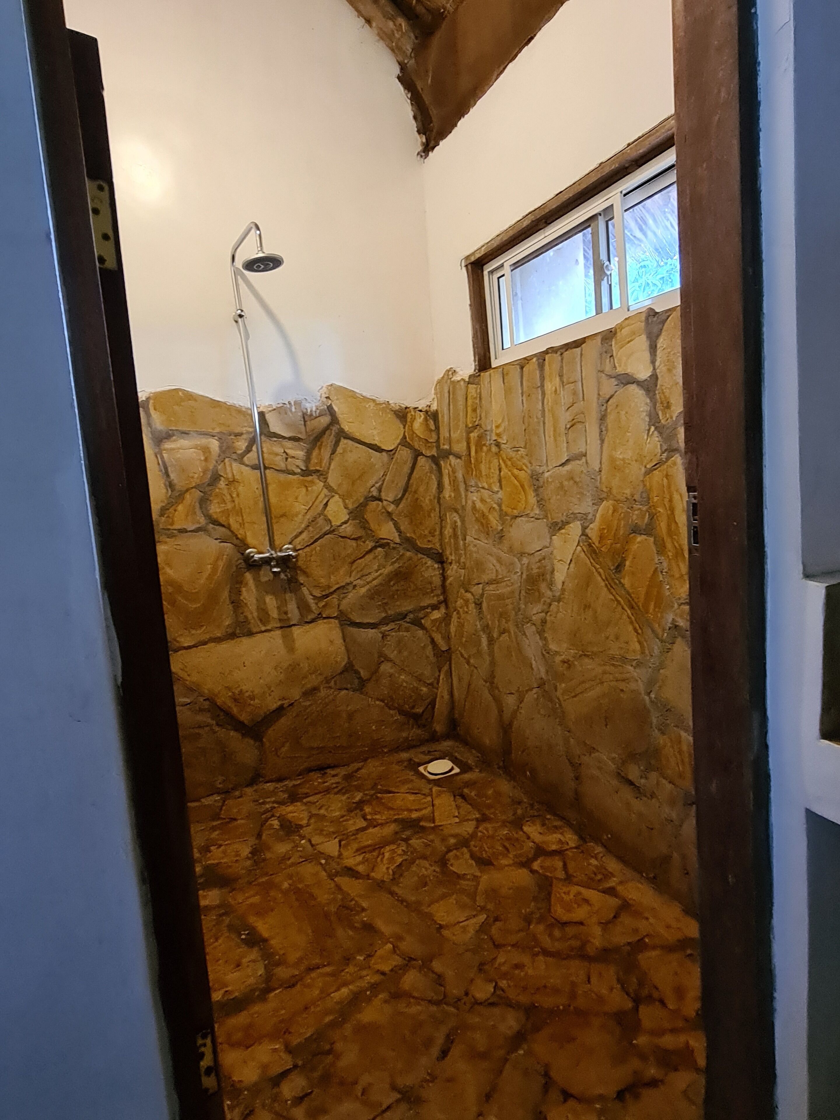 A stone-walled shower area with a window above.