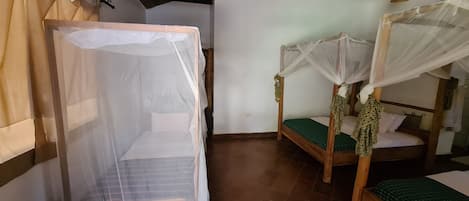 Una habitación con dos camas de madera, cada una con dosel, y una pequeña cesta tejida.
