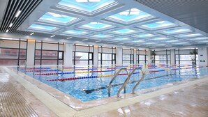 An indoor swimming pool with clear lanes, a tiled floor, and a ceiling with skylights. - Zhengfangyuan International Hotel (Zhengzhou)