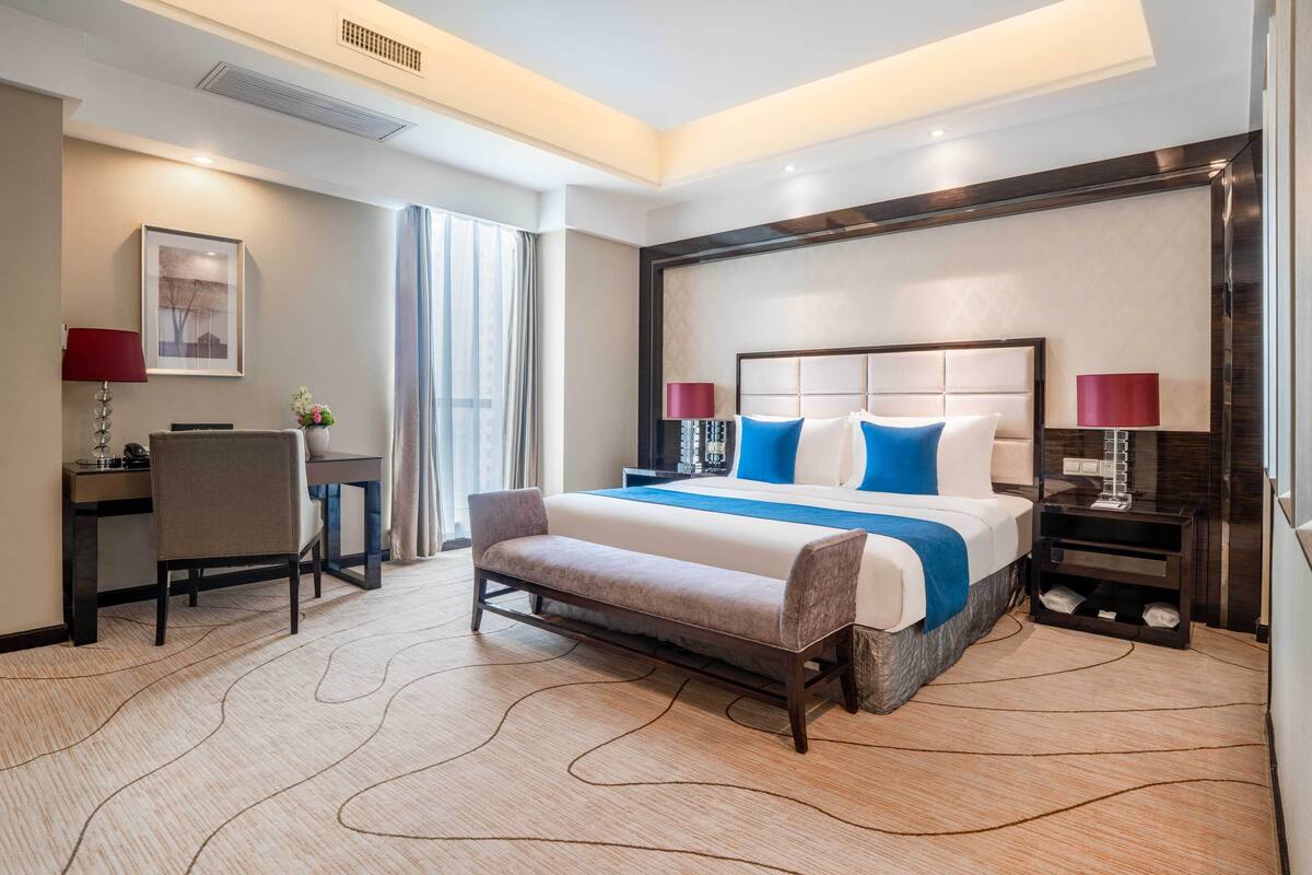 Una habitación de hotel moderna con una cama grande, un escritorio y un banco.
