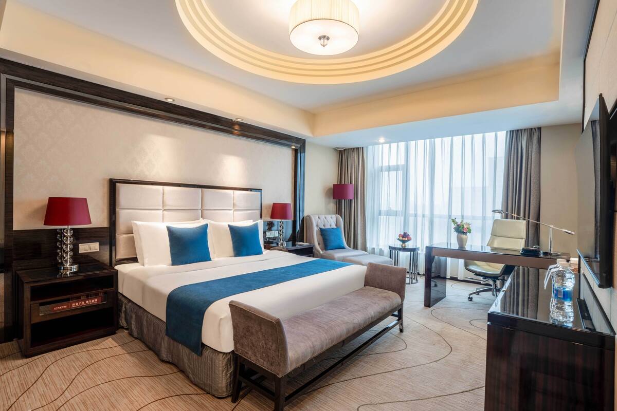 Una habitación de hotel con una cama grande, un escritorio, una silla y un sofá.
