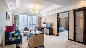 A hotel room with a seating area, a television, a desk, and a large window with curtains. - Zhengfangyuan International Hotel (Zhengzhou)