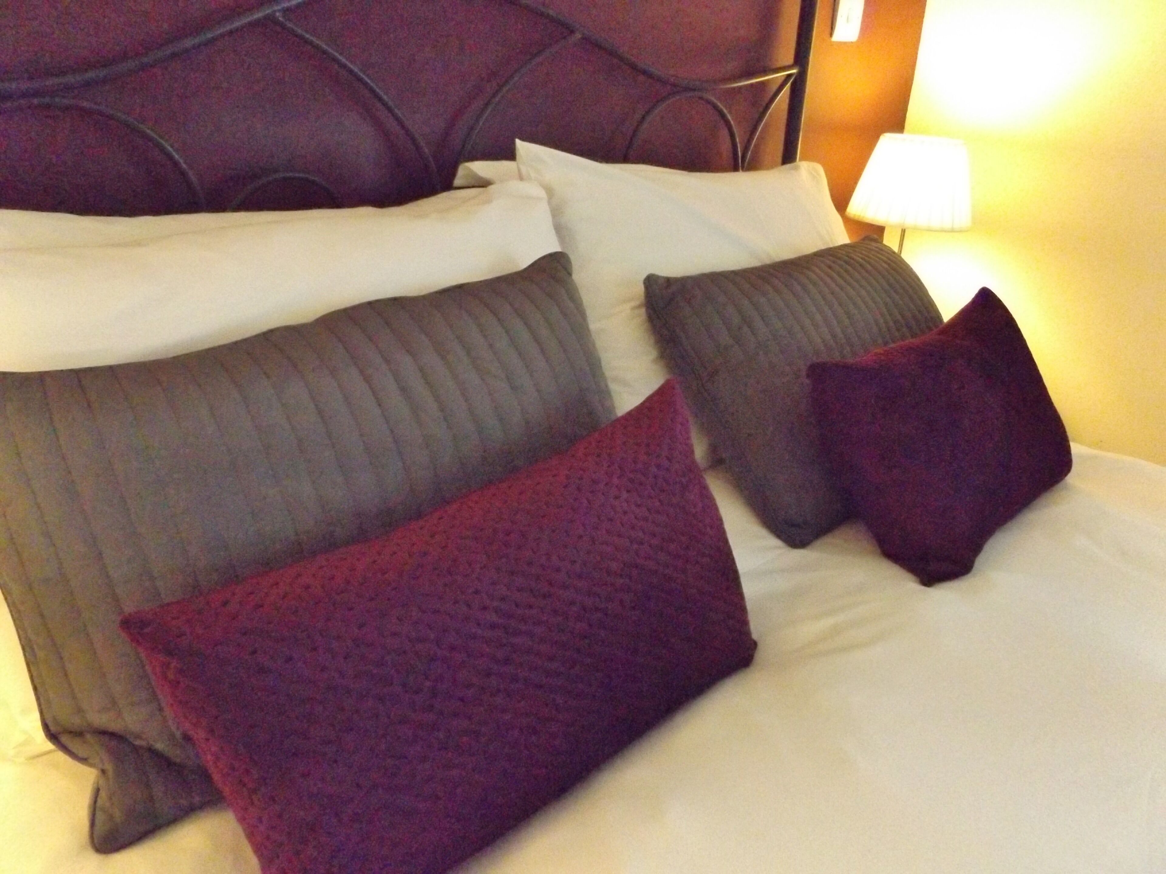 A neatly made bed with multiple pillows and a headboard.