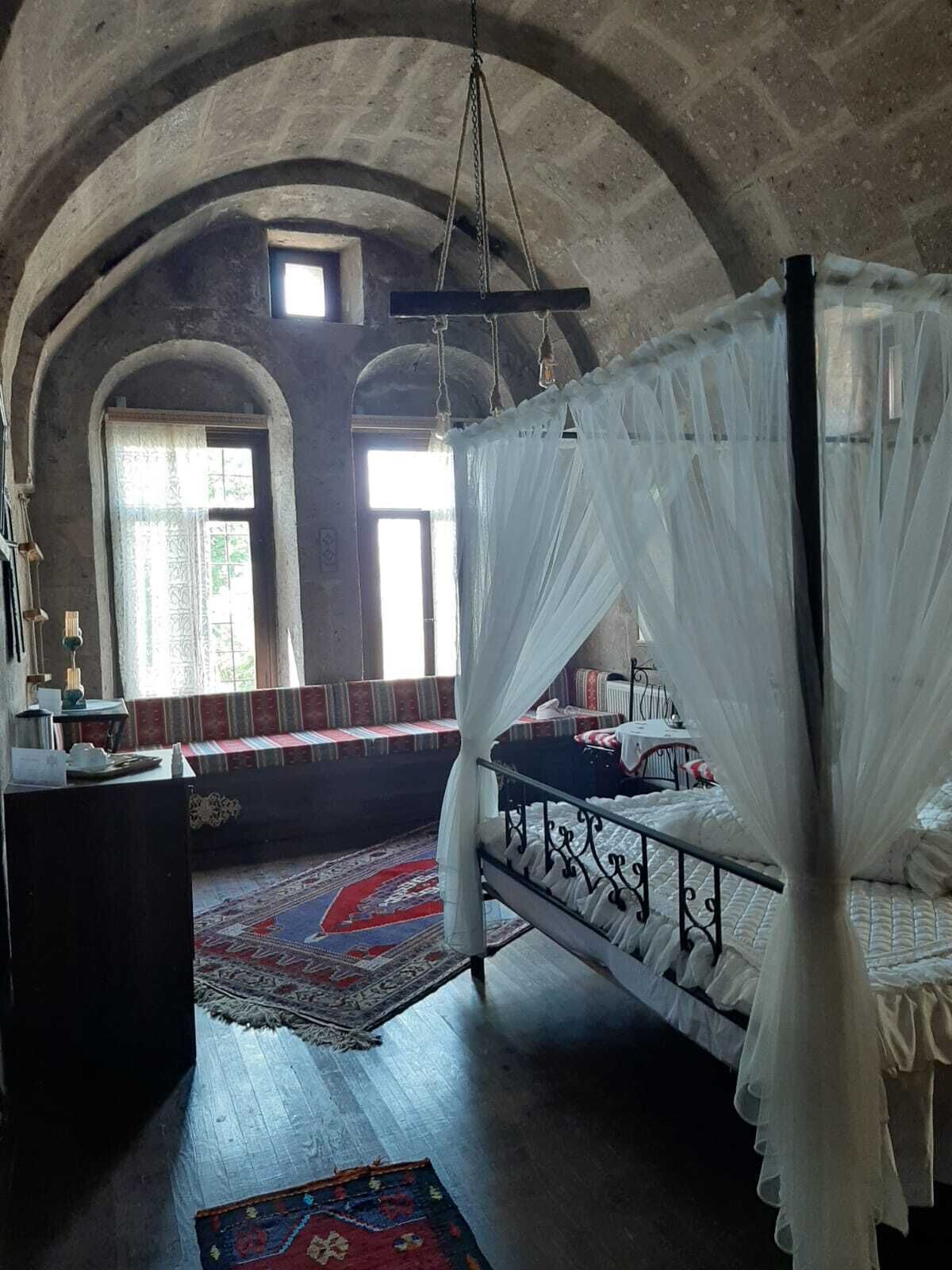 Une chambre avec un lit à baldaquin, un bureau en bois et un banc agrémenté de coussins.