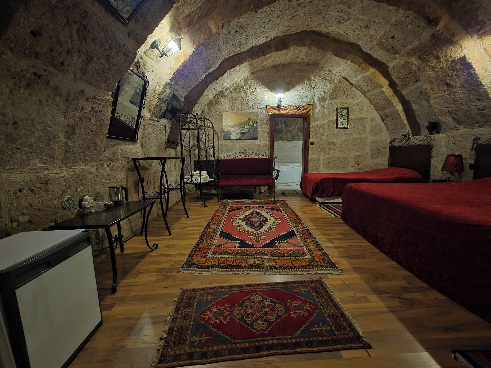 A rustic room with a vaulted ceiling, a bed, a sofa, a small table, and a chair.