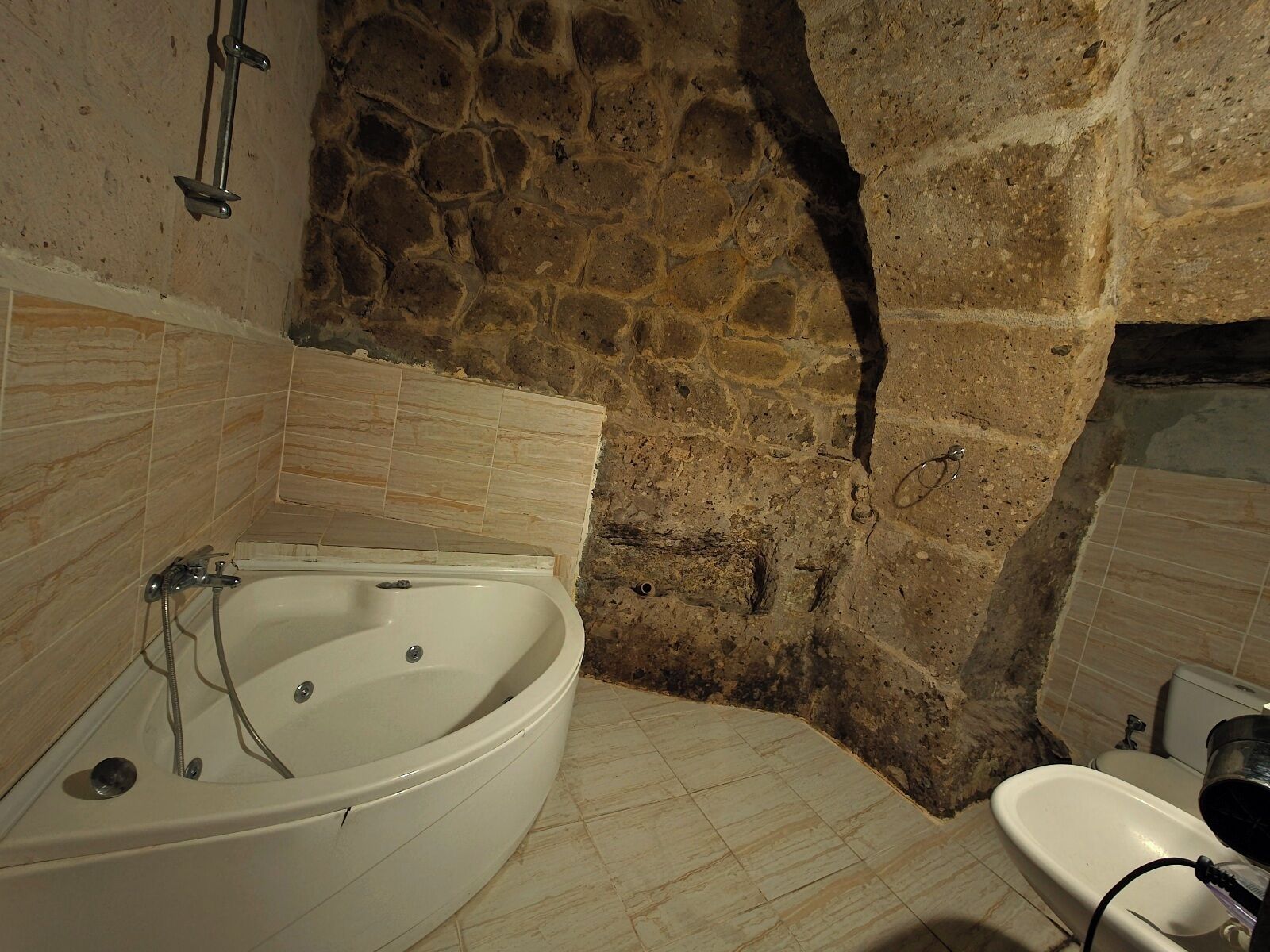 A bathroom with a stone wall, a bathtub, and a sink.