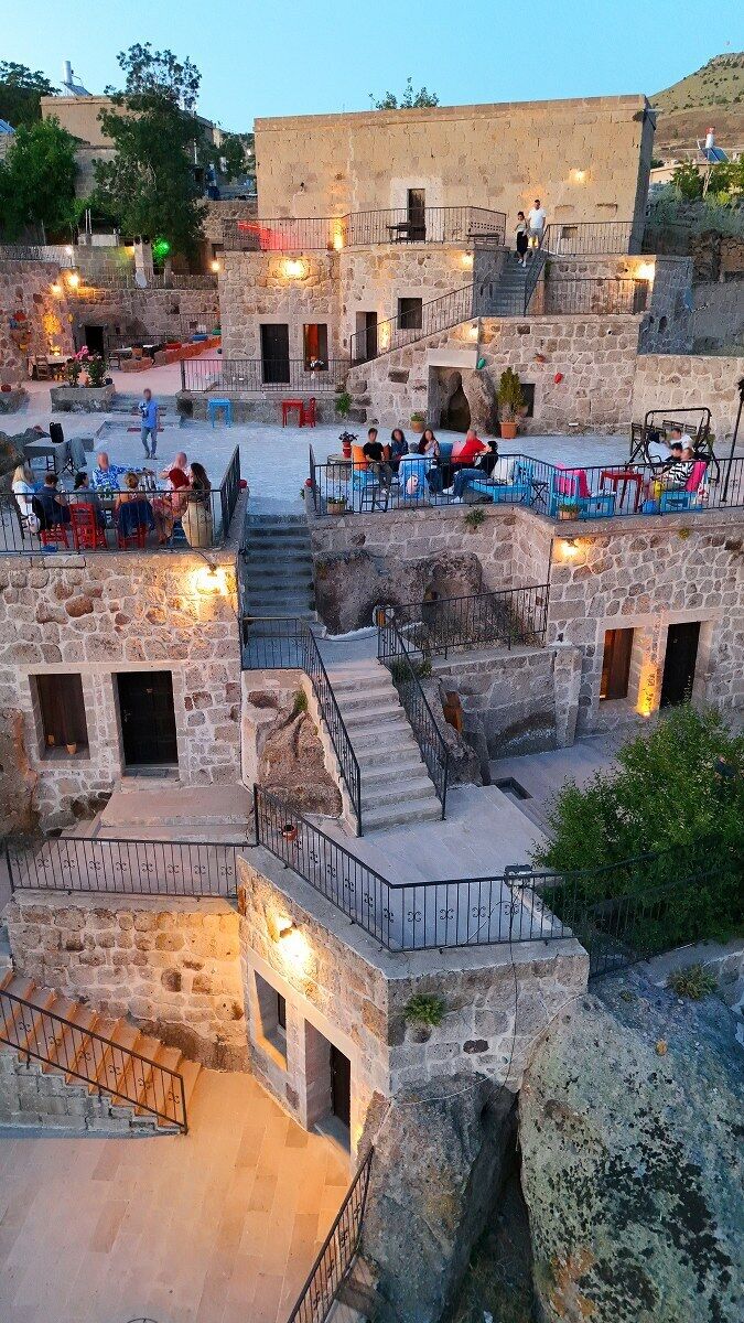 Un edificio de piedra con zonas de estar al aire libre y una escalera.