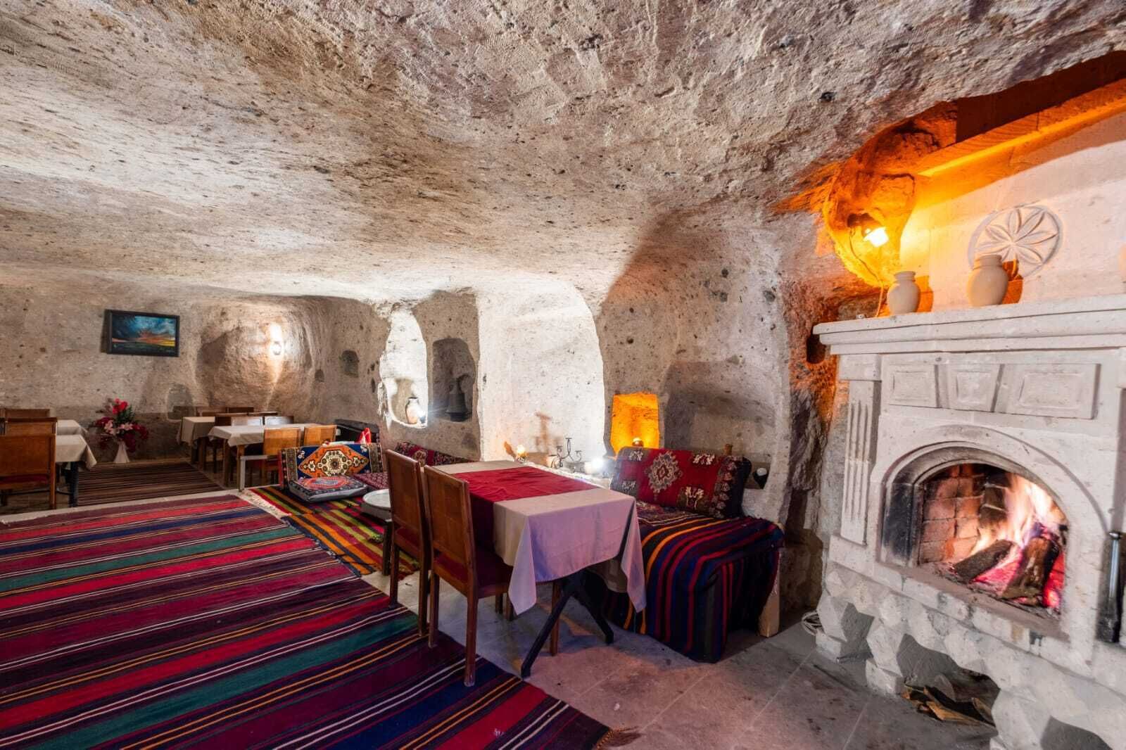 A rustic interior with a stone fireplace, wooden furniture, and colorful rugs.