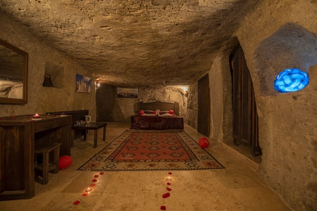 A rustic room with a bed, a wooden desk, and a patterned rug.