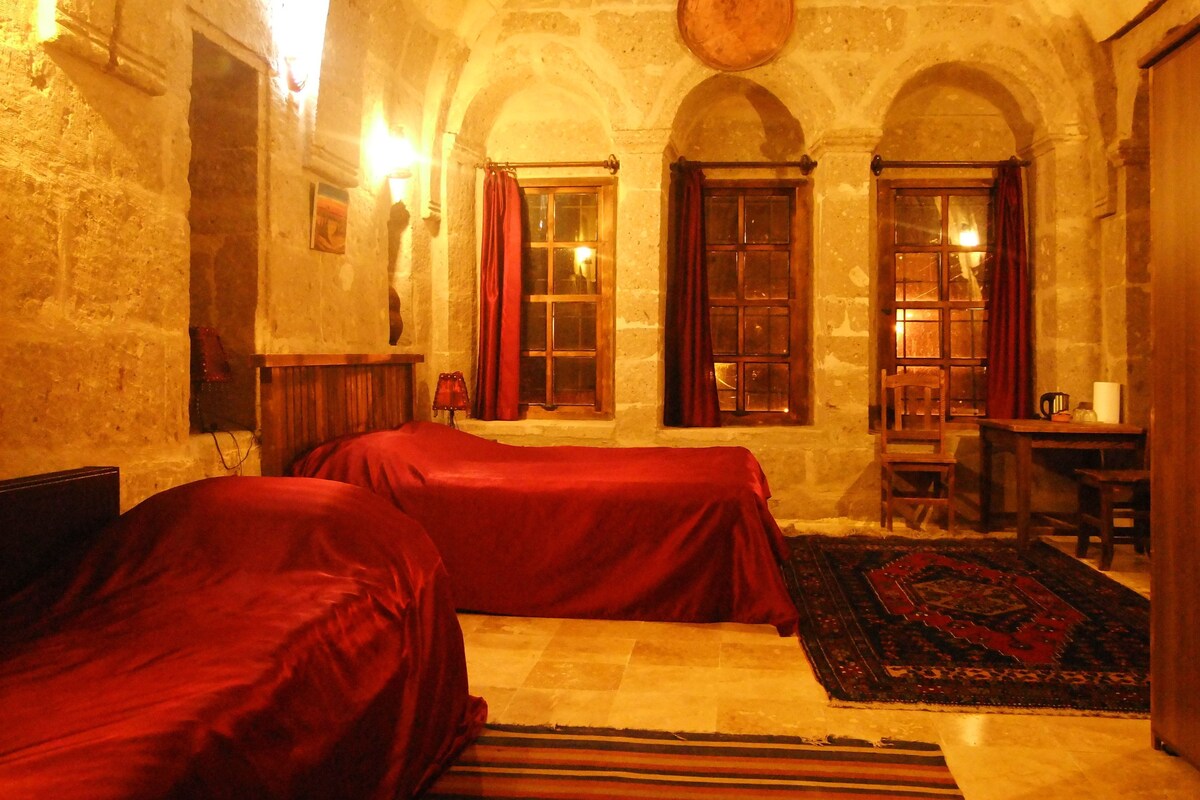Une chambre avec deux lits, un bureau et une grande fenêtre avec des rideaux.