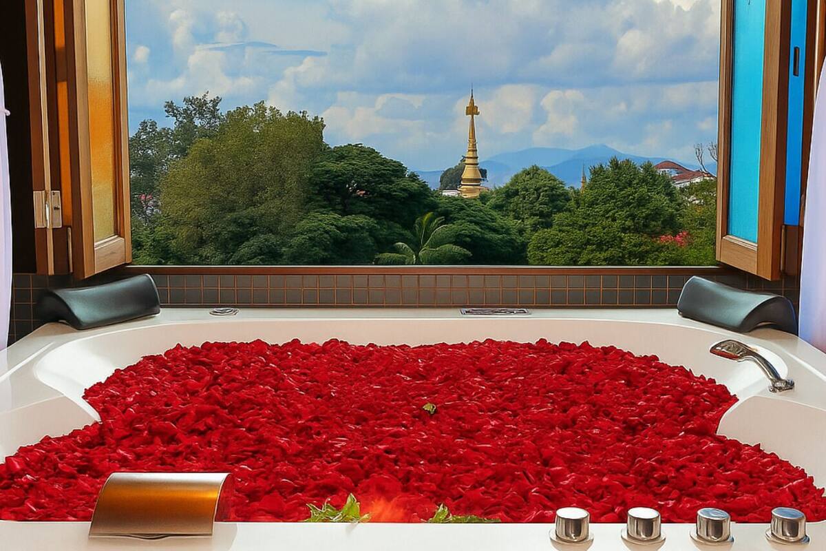 Une baignoire remplie de pétales de roses rouges, un robinet de baignoire et, en arrière-plan, une vue sur un temple.