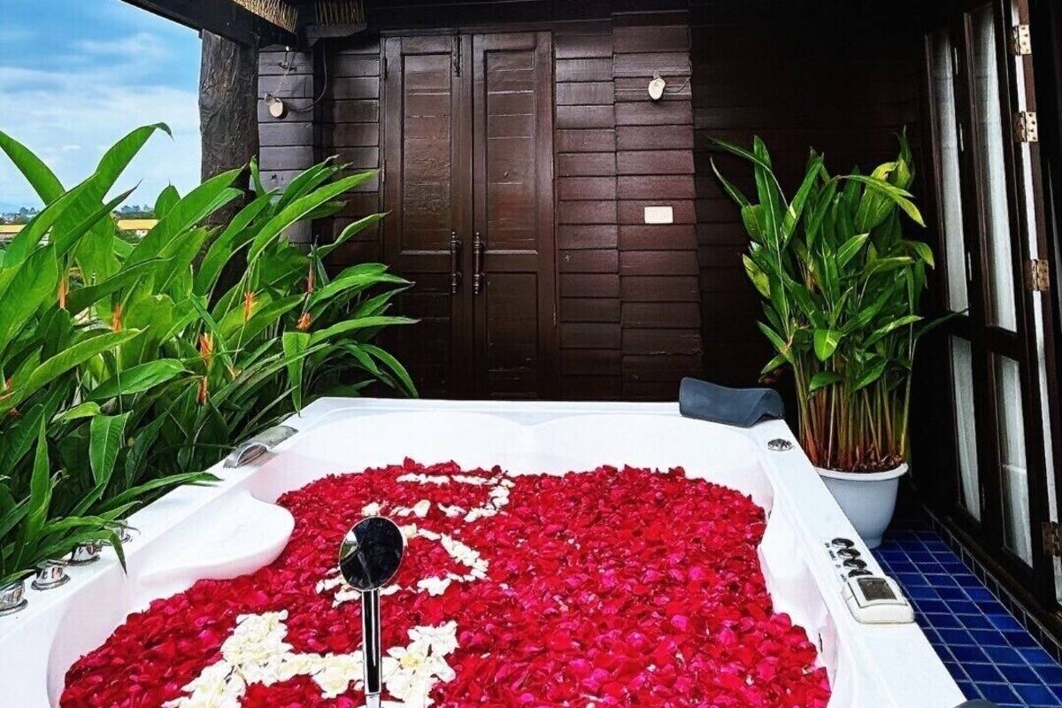 A traditional building with a tiled roof, a wooden door, and a small garden area with a hot tub filled with rose petals.