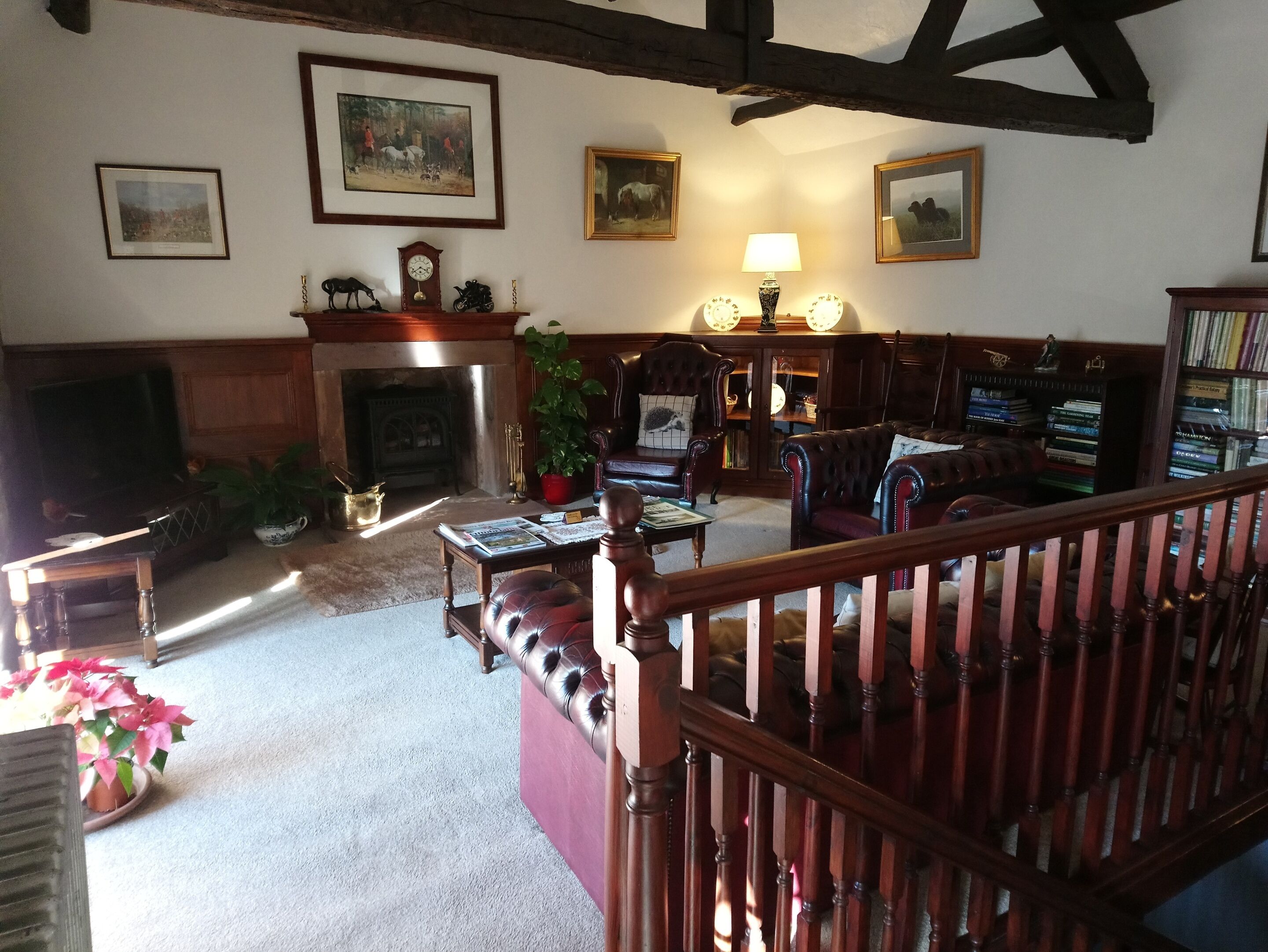 A traditional living room with a fireplace, leather furniture, and a bookshelf.