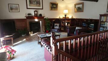 A traditional living room with a fireplace, leather furniture, and a bookshelf.