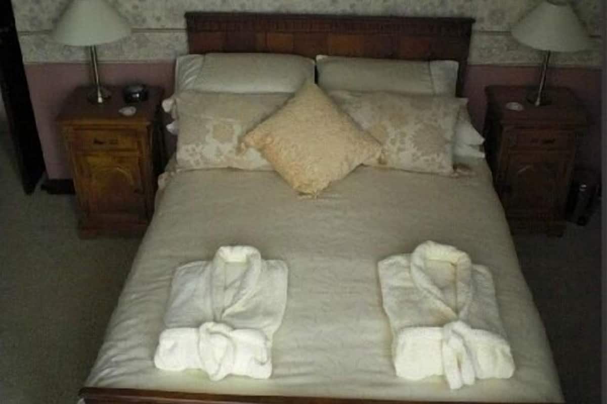 A neatly made bed with two sets of towels folded at the foot.