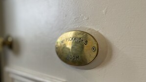 Un timbre de latón con la inscripción "NE PIKWICK'S ROOM" en una puerta blanca.