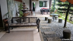 A patio area with a wooden bench, a dining table with chairs, and a sign for 'The Manor Cafe'. - Tagaytay Wingate Manor (Tagaytay)