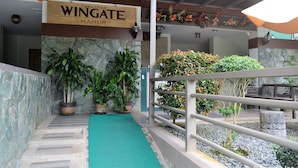 A hotel entrance with a sign reading "Wingate Manor," potted plants, a green carpeted pathway, and a stone wall. - Tagaytay Wingate Manor (Tagaytay)