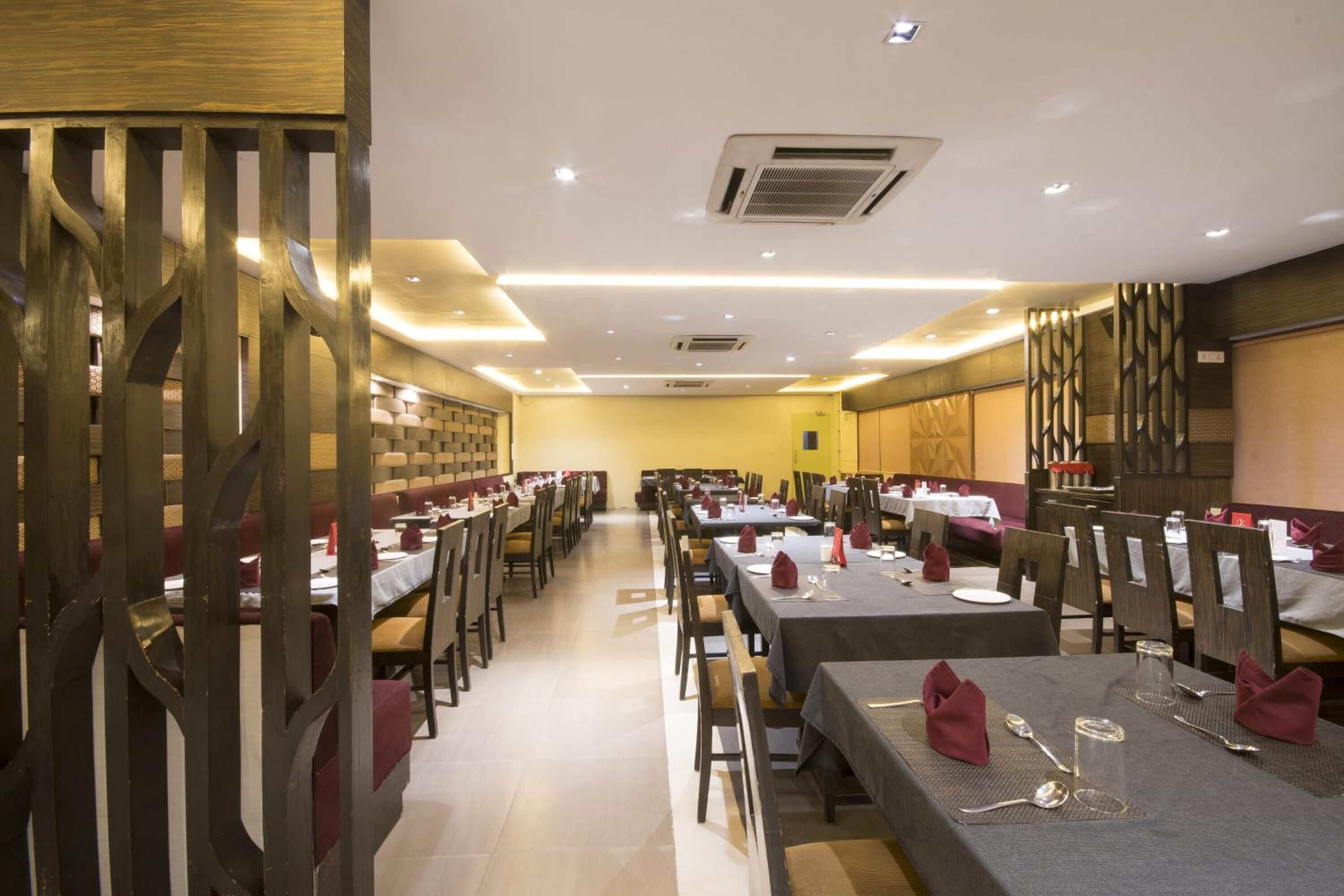 A restaurant with multiple dining tables, chairs, and a decorative partition.
