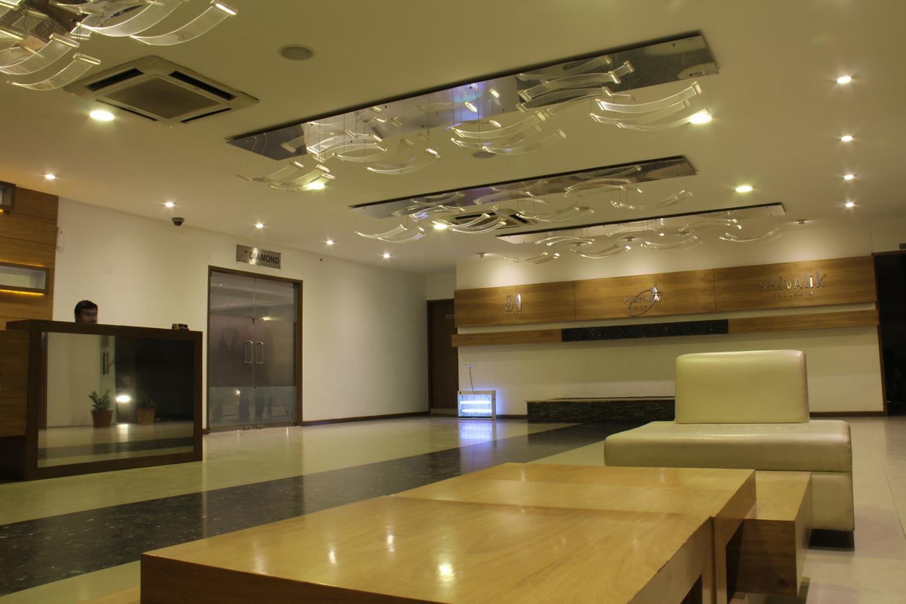 A modern lobby with a reception desk, a seating area, and a wooden wall with a sign.
