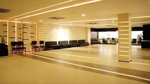 A spacious lobby with a reception desk, seating area, and a large window. - Hotel Platinum Inn (Ahmedabad)