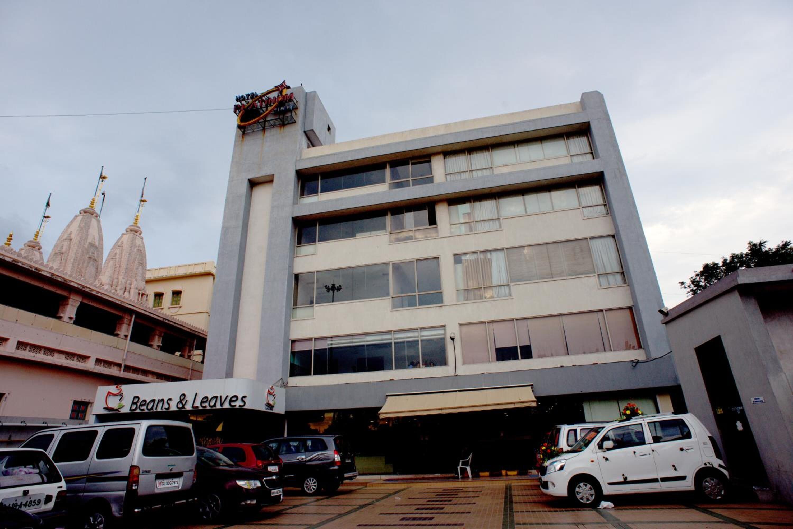 Un edificio de varios pisos con fachada plana y ventanas grandes. En la planta baja, hay un letrero que dice "Beans & Leaves".